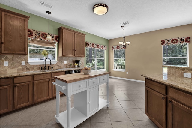 kitchen featuring backsplash, light tile patterned floors, sink, and a healthy amount of sunlight