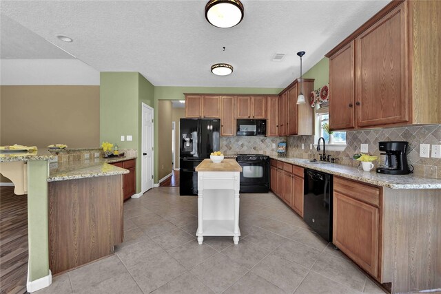 kitchen featuring a textured ceiling, black appliances, decorative light fixtures, tasteful backsplash, and sink