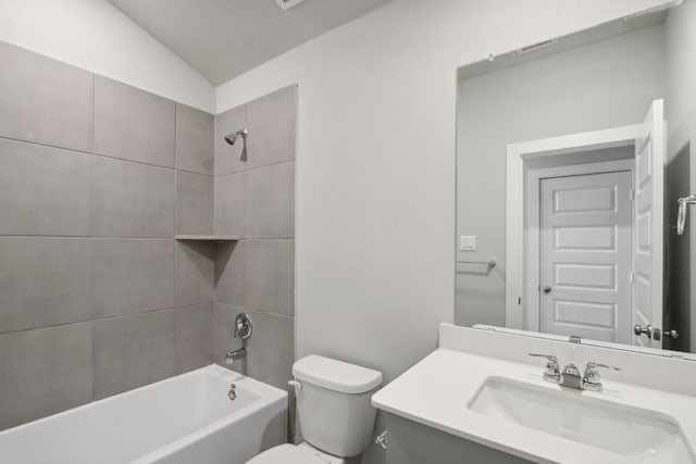 full bathroom with tiled shower / bath, vanity, toilet, and vaulted ceiling