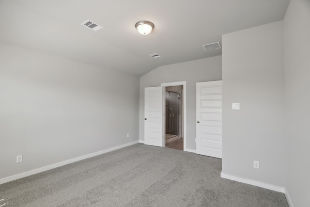 spare room featuring carpet flooring and vaulted ceiling