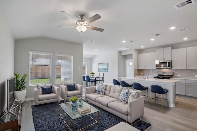 living room featuring ceiling fan, vaulted ceiling, a healthy amount of sunlight, and light hardwood / wood-style floors