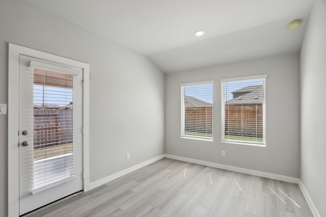 spare room featuring lofted ceiling, a wealth of natural light, and light wood-type flooring