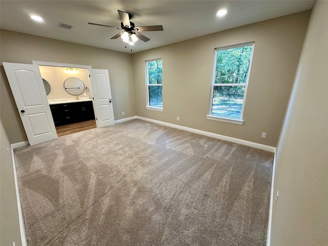 unfurnished bedroom with ensuite bath, ceiling fan, and carpet flooring