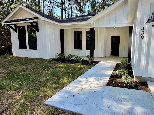 doorway to property featuring a lawn and a patio area