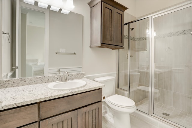 bathroom with a shower with door, vanity, and toilet