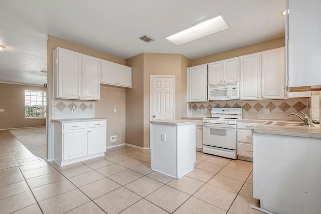 kitchen featuring sink, a center island, light tile patterned floors, white cabinetry, and white appliances