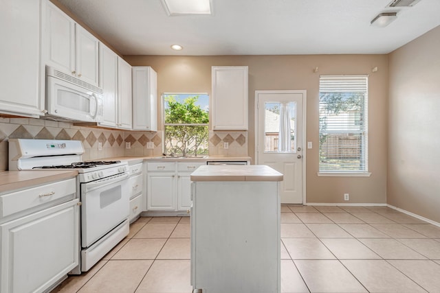 kitchen featuring tasteful backsplash, light tile patterned floors, white cabinetry, sink, and white appliances