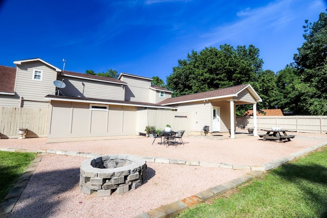 back of property featuring a fire pit, an outbuilding, and a patio