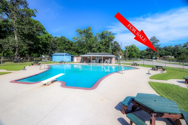 view of pool with a patio and a diving board