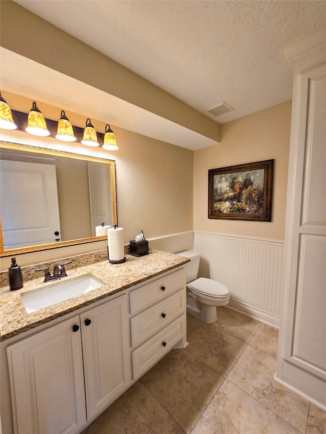 bathroom with tile patterned floors, vanity, a textured ceiling, and toilet