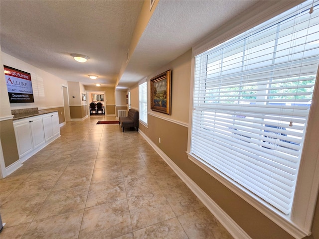 hallway with light tile patterned floors and a textured ceiling