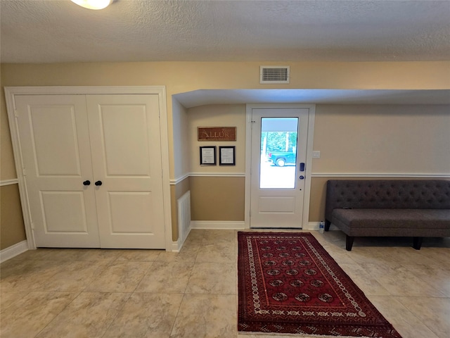 tiled entryway featuring a textured ceiling