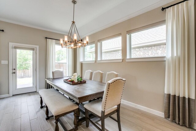 dining area featuring light wood-type flooring, ornamental molding, and an inviting chandelier