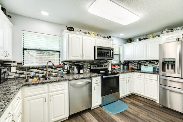 kitchen featuring stainless steel appliances, dark hardwood / wood-style floors, decorative backsplash, white cabinets, and sink