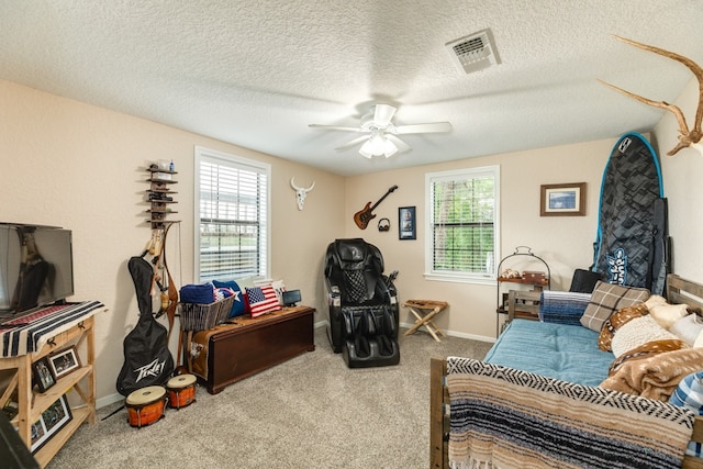 interior space featuring a textured ceiling, plenty of natural light, ceiling fan, and carpet floors