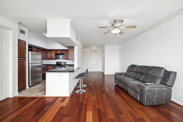 kitchen featuring ceiling fan, dark hardwood / wood-style flooring, kitchen peninsula, a kitchen bar, and appliances with stainless steel finishes