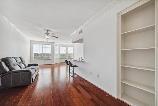 living room featuring ceiling fan, dark hardwood / wood-style flooring, crown molding, and built in shelves