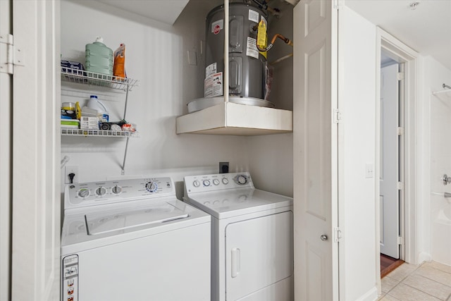 washroom with water heater, washer and clothes dryer, and light tile patterned flooring