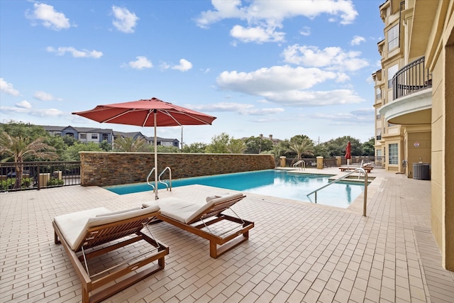 view of pool with cooling unit and a patio area