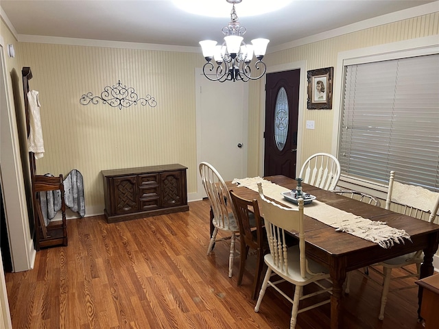 dining space featuring wood-type flooring, ornamental molding, and a chandelier