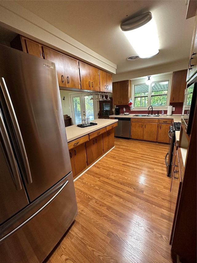 kitchen with stainless steel appliances, sink, and light wood-type flooring