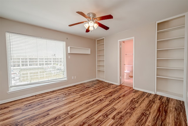 unfurnished bedroom featuring wood-type flooring, ceiling fan, and connected bathroom