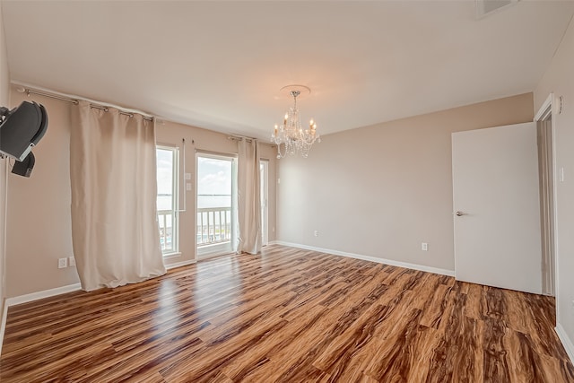 empty room featuring an inviting chandelier and hardwood / wood-style floors