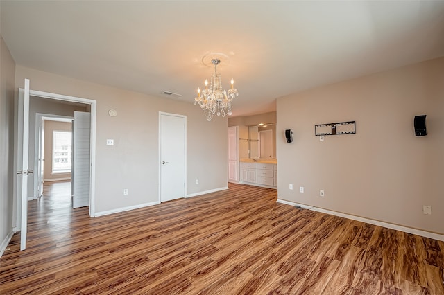 spare room featuring a notable chandelier and light hardwood / wood-style floors