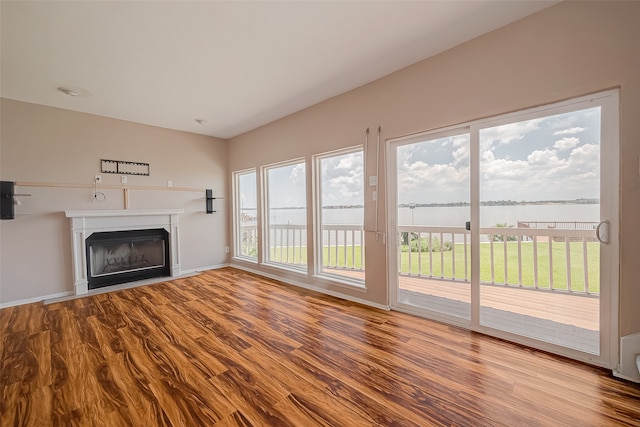 unfurnished living room featuring hardwood / wood-style floors and a water view