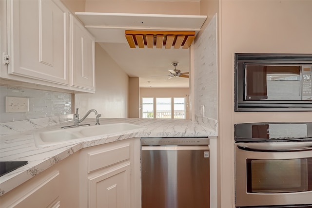 kitchen with tasteful backsplash, white cabinets, stainless steel appliances, ceiling fan, and sink