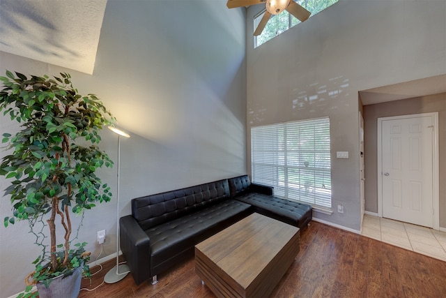 living room featuring ceiling fan, wood-type flooring, and a high ceiling