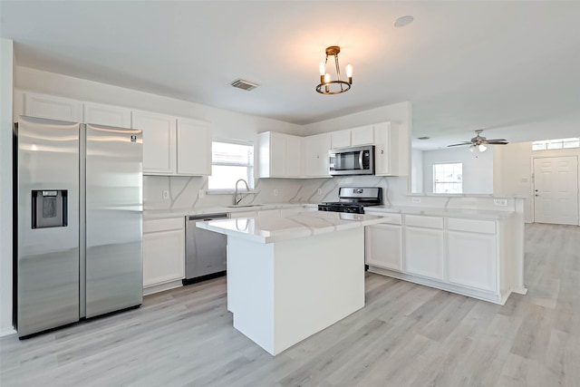 kitchen featuring appliances with stainless steel finishes, a center island, a wealth of natural light, and pendant lighting