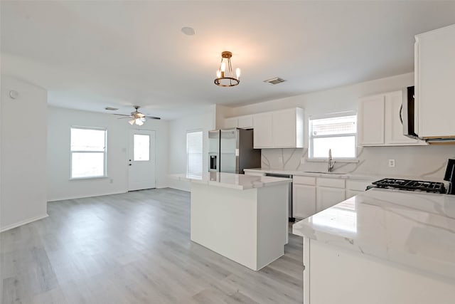 kitchen featuring appliances with stainless steel finishes, a center island, decorative light fixtures, and a wealth of natural light