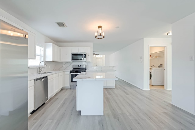 kitchen featuring white cabinetry, a kitchen island, decorative light fixtures, and appliances with stainless steel finishes