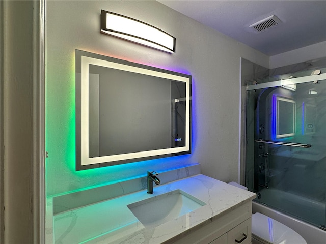 full bathroom featuring vanity, toilet, and bath / shower combo with glass door