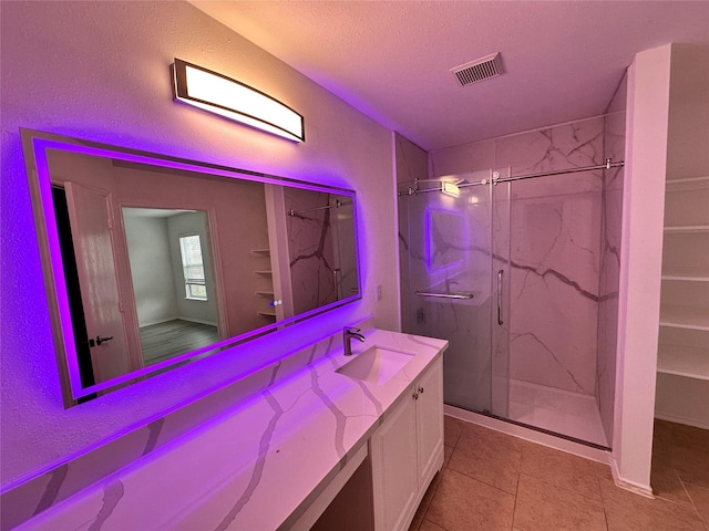 bathroom featuring tile patterned flooring, vanity, a shower with shower door, and a textured ceiling