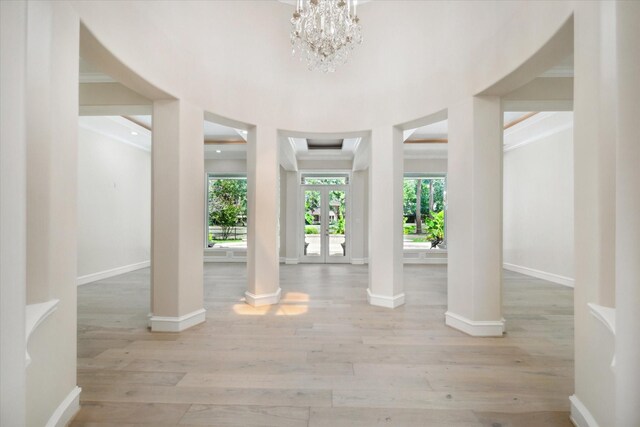 foyer entrance featuring french doors, an inviting chandelier, light wood-type flooring, and ornamental molding