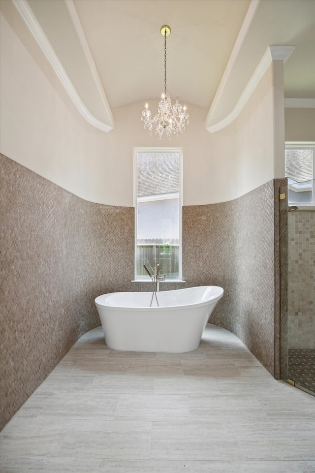 bathroom featuring lofted ceiling, plenty of natural light, a chandelier, and a tub