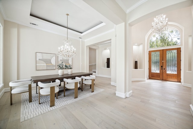 dining room with a raised ceiling, light hardwood / wood-style floors, a chandelier, and french doors