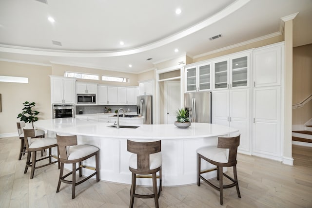 kitchen featuring white cabinetry, appliances with stainless steel finishes, a breakfast bar, a spacious island, and light hardwood / wood-style floors