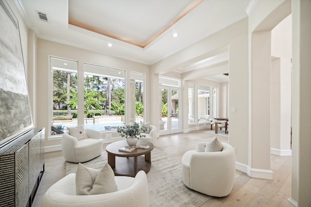 living area featuring a raised ceiling, light hardwood / wood-style flooring, french doors, and a wealth of natural light