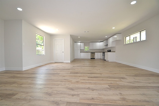 unfurnished living room featuring sink and light hardwood / wood-style floors