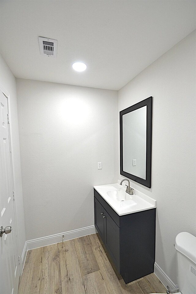 bathroom with vanity, toilet, and hardwood / wood-style floors