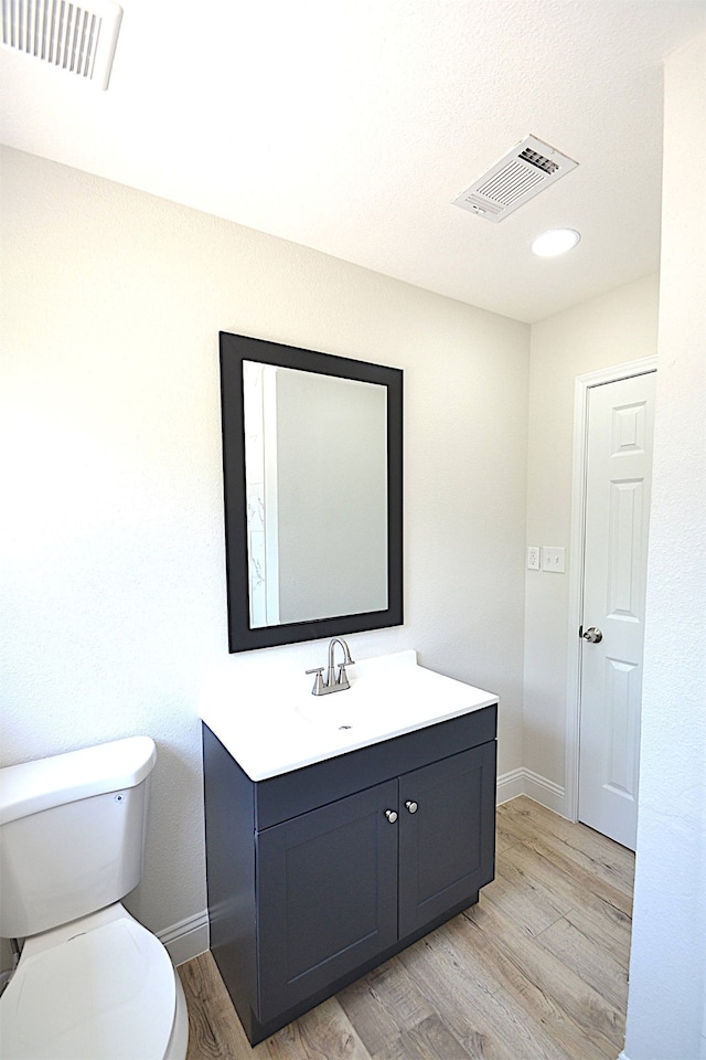 bathroom featuring toilet, vanity, and hardwood / wood-style flooring