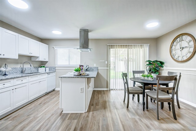 kitchen featuring island exhaust hood, light wood-type flooring, light stone counters, and a center island