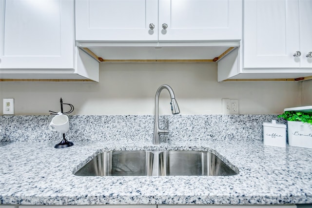 interior space with light stone countertops, sink, and white cabinetry