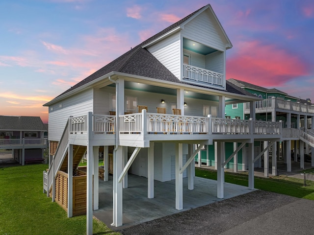 back house at dusk featuring a lawn and a deck