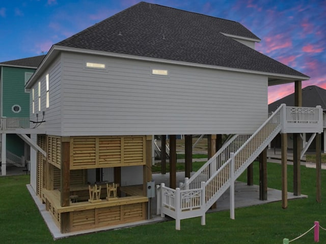 back house at dusk with a deck and a lawn