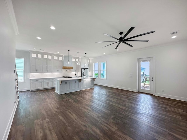 unfurnished living room with ceiling fan, sink, ornamental molding, and dark hardwood / wood-style floors