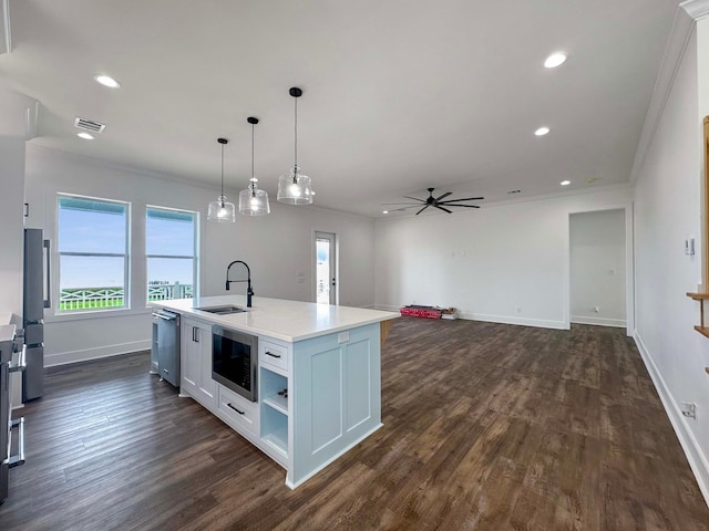 kitchen with appliances with stainless steel finishes, a kitchen island with sink, white cabinetry, ornamental molding, and dark wood-type flooring